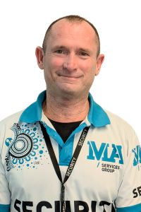 A security guard working at 15 William Street wearing a white polo shirt with a blue collar and a lanyard